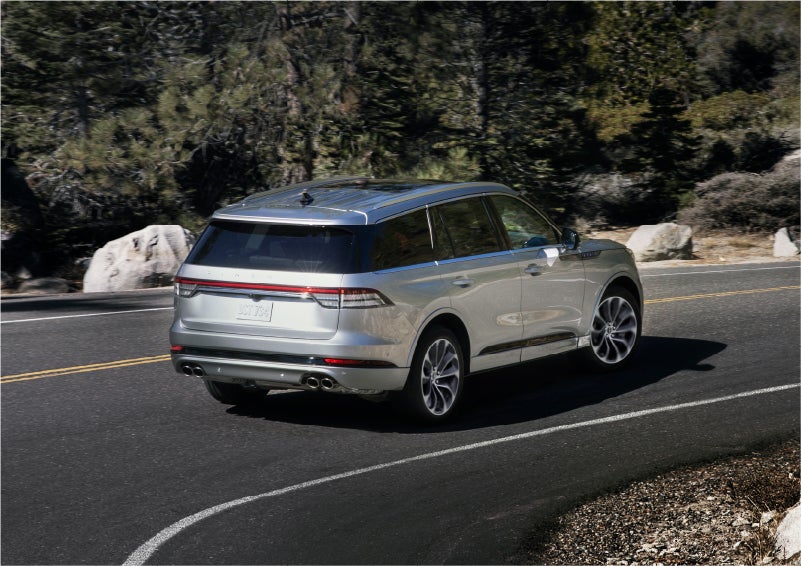 A 2023 Lincoln Aviator® Grand Touring model is shown being driven on a tight turn of a mountain road | Lincoln North Miami in North Miami FL
