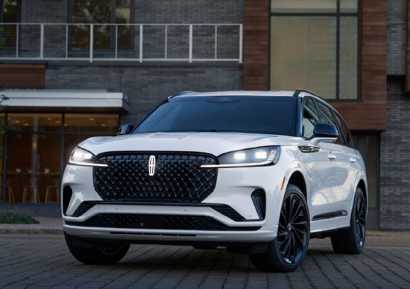 A 2026 Lincoln Aviator® Reserve model is shown with the available Jet Appearance Package parked near a restaurant. | Lincoln North Miami in North Miami FL