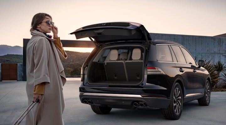 A woman approaches a 2026 Lincoln Aviator® SUV with its rear liftgate open. | Lincoln North Miami in North Miami FL
