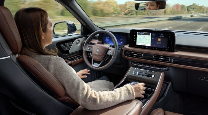 A 2026 Lincoln Aviator® SUV is being driven hands-free on a highway near a forest | Lincoln North Miami in North Miami FL