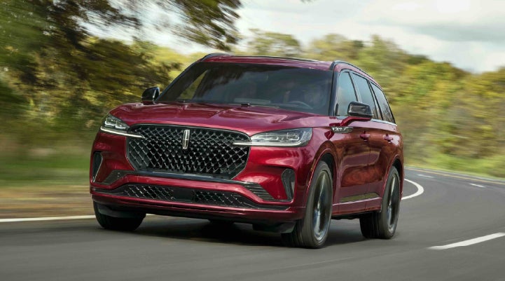 A 2027 Lincoln Aviator® SUV is being driven on a country road | Lincoln North Miami in North Miami FL