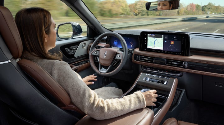A 2027 Lincoln Aviator® SUV is being driven hands-free on a highway lined with trees. | Lincoln North Miami in North Miami FL