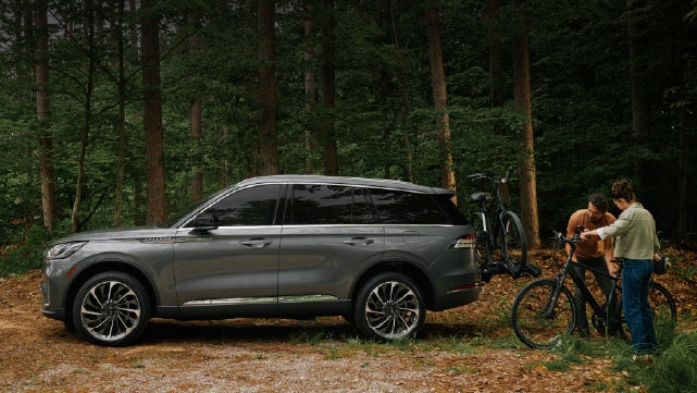 A father and son load e-bikes on a bike rack attached to a 2027 Lincoln Aviator® SUV. | Lincoln North Miami in North Miami FL