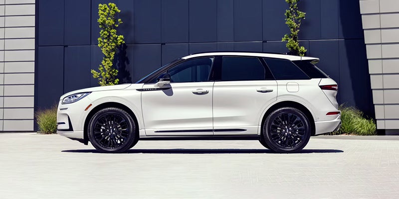 Side profile view of a white SUV parked in front of a modern building exterior